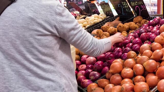 Shoppers Selecting Fresh Onions and Potatoes at an Outdoor Market Stall