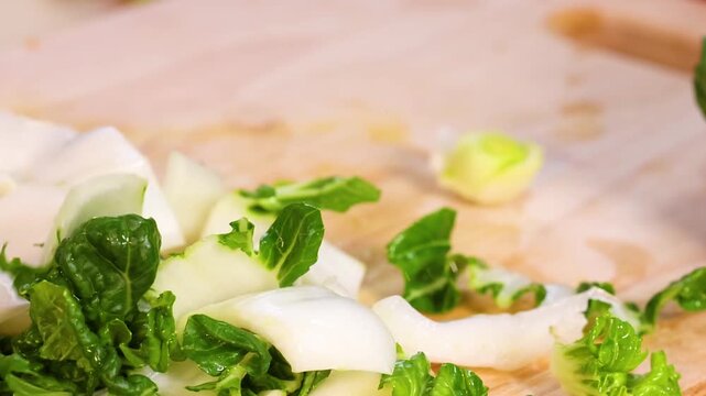 Close Up of Hands Tearing Fresh Green Bok Choy Leaves on Board