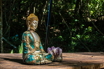 Meditating Buddha statue and amethyst in a serene natural setting in Brazil, symbolizing peace and spirituality.