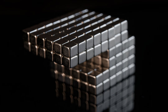 Geometric arrangement of metallic magnetic cubes in an offset pattern. Concept of balance, physics, and structural logic isolated on black. Photo
