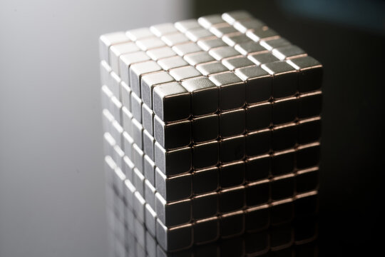 Large square block assembled from tiny metallic magnetic cubes. Concept of structural integrity, logic, science, and educational problem solving. Photo