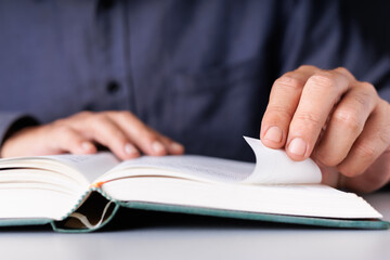 Man Folding Book Page to Mark Important Content While Reading