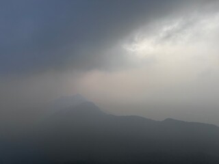 A scenic view of Parvathamalai mountain peak rising above clouds under a dramatic sky in Tamil Nadu, India. Rocky terrain, misty atmosphere, and high-altitude landscape create a serene and adventurous