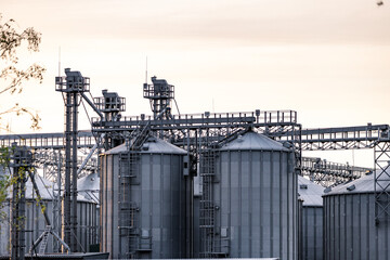 Obraz premium Large metallic storage tanks and silos are situated within an industrial complex, showcasing a clear blue sky and operational infrastructure during daytime