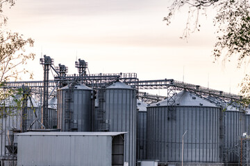 Obraz premium Large metallic storage tanks and silos are situated within an industrial complex, showcasing a clear blue sky and operational infrastructure during daytime