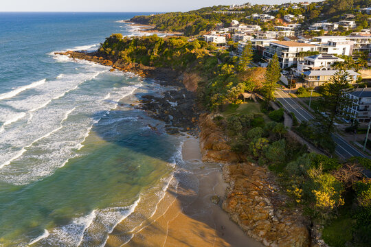 Aerial view of waterfront property high above a rugged coastline and crashing waves
