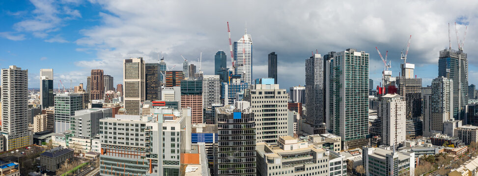 Aerial panorama view of billowing cloud over a wide city skyline covered in construction cranes