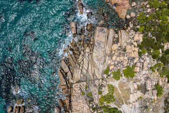 Aerial image capturing the turquoise waters and rocky shoreline of Rose Bay, Bowen
