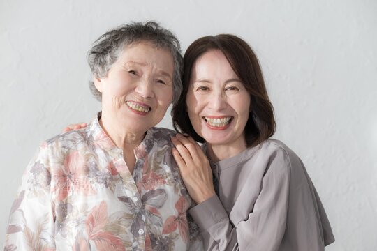 娘と高齢の母の笑顔の寄り添うポートレーのカメラ目線クローズアップ　介護や親子のイメージ