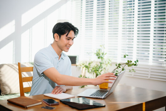 Asian man managing personal finance and household budget at home office. Smart money management, online banking, savings and modern work from home