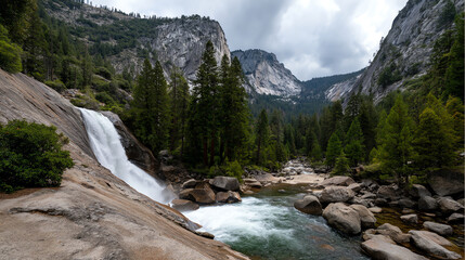 Waterfall cascades into a rocky river surrounded by dense pine forest and towering granite cliffs under a cloudy sky in a mountainous landscape