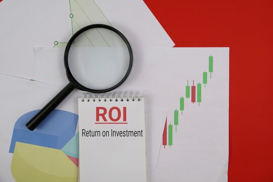 ROI Concept With Business Charts, Pie Diagram, And Magnifying Glass For Investment Analysis. isolated on a red surface. - Powered by Adobe