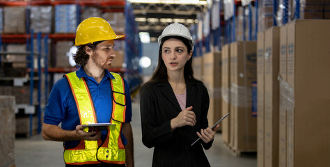 Warehouse manager and logistics worker collaborating with digital tablets in storage facility, showcasing teamwork, technology integration.