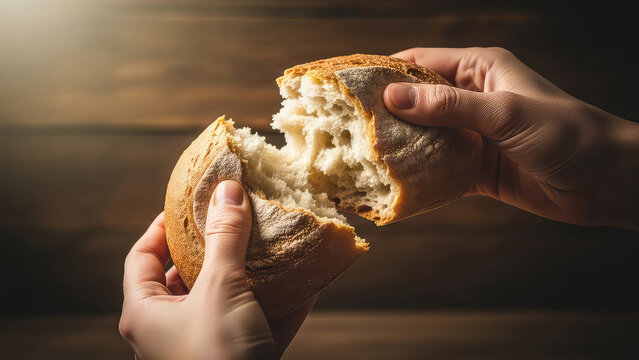Hands breaking a loaf of bread in half