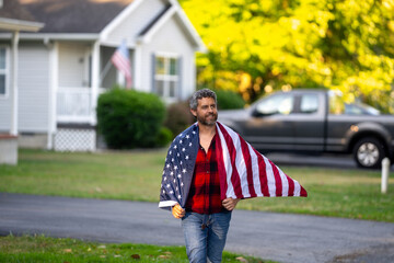 Mature man hold American Flag near suburban house. USA Flag freedom. American Flag near American House. American man representing national pride.