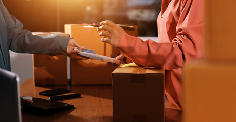 Startup SME small business entrepreneur of freelance Asian woman wearing apron using laptop and box to receive and review orders online to prepare to pack sell to customers, online sme business ideas.