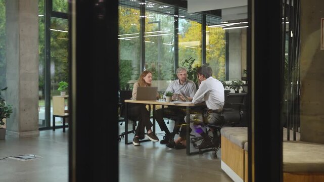 Business people in the office behind a glass partition in casual clothes, with blurred bokeh background.