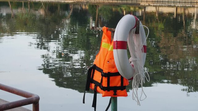 Life Jacket and Buoy: Orange Safety Vest Floating Device Water Rescue Equipment Pool Reflection Background