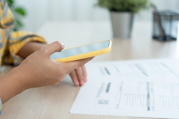 woman use phone to scan barcode or QR codes to pay credit card bill after receiving document invoice online. payment, receive, paying electricity, digital payments, technology, scanning, financial