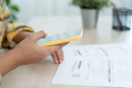 woman use phone to scan barcode or QR codes to pay credit card bill after receiving document invoice online. payment, receive, paying electricity, digital payments, technology, scanning, financial - Powered by Adobe