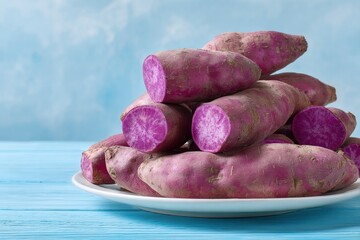 A vibrant pile of fresh purple sweet potatoes is beautifully arranged on a clean white plate, creating an eye-catching display of natural produce. Several tubers are strategically cut in half, showcas