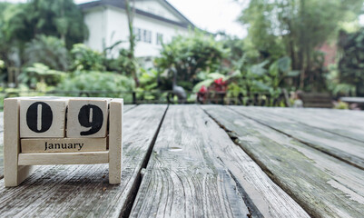 wooden cube calendar for January 9th place on old table in sunny garden background
