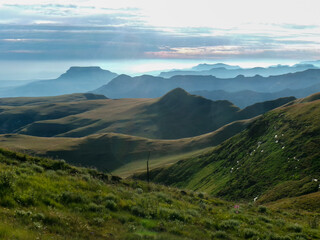 Fototapeta premium Dramatic mountain landscape of the Drakensberg Mountains with steep cliffs and rolling green valleys in South Africa
