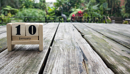 wooden cube calendar for January 10th place on old table in sunny garden background