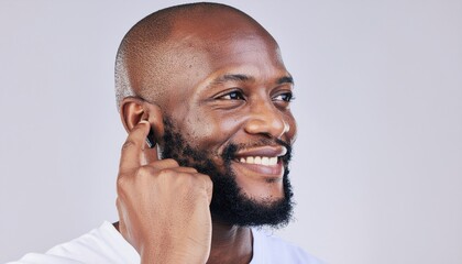 Smiling Man Adjusting His Ear While Listening in a Light Studio Background During Portrait Session