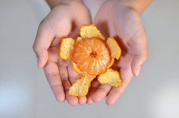 Hand-held Citrus Offering: A pair of hands cradles a peeled citrus fruit, presenting its vibrant segments, a symbol of freshness and a moment of mindful enjoyment.