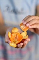 Zesty Citrus Pleasure: A hand peels a vibrant mandarin orange, revealing juicy segments. Capturing the fresh and inviting appeal of this tasty treat