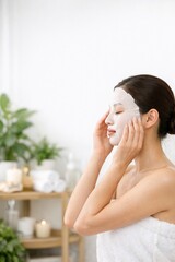 Embrace of Rejuvenation: A serene individual indulges in a spa-like experience, applying a refreshing facial mask with a backdrop of plants and candles