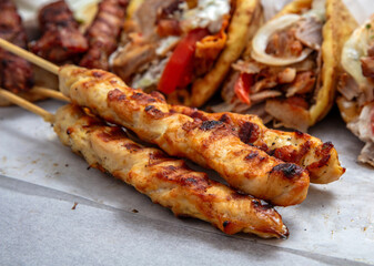 Gyro sliced meat pita bread wraps, chicken souvlaki skewers, traditional street food, closeup