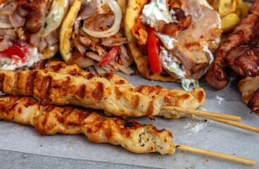 Gyro sliced meat pita bread wraps, chicken souvlaki skewers, traditional street food, closeup
