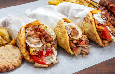 Gyros doner shawarma wraps stuffed with roasted meat, onions, tomato and tzatziki, closeup