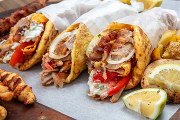 Doner gyro or shawarma wraps stuffed with roasted meat, onions, tomato and tzatziki, closeup