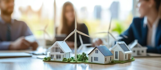 Miniature houses and wind turbines on a table, business meeting
