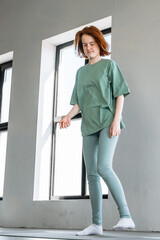 Young woman in green outfit practicing movement in a bright indoor space