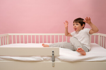 Little boy showing his tongue while sitting in bed. Child making funny face for kid healthcare and daycare ad. Child aged 4 years (four years old)