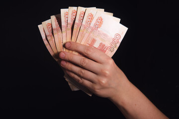 Female hand holding a fan of five thousand ruble banknotes, concept of financial success, wealth, and Russian economy.
