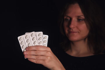 Woman holding several blister packs of white oval pills. Concept of medicine, pharmacy, or self-medication with drug prescription for health and pain.