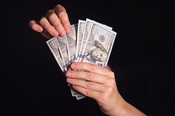 Woman holding five 100 dollar banknotes in her hands. Concept of personal finance, salary, income, wealth, and saving money.