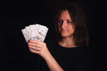 Woman looking at fan of dollar bills, a concept illustrating financial planning, savings, or income. Investment and budget management for personal finance.