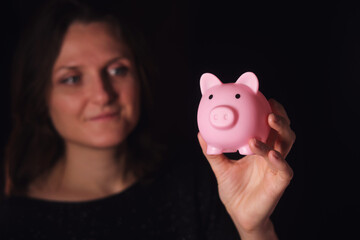 Woman holding a pink piggy bank in her hand, representing saving money and financial planning. Concept of investment, banking, and wealth growth.