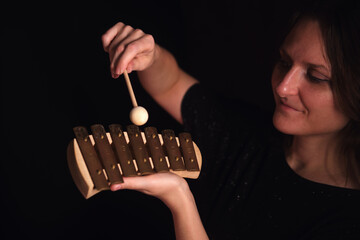Woman playing a small glockenspiel with a mallet. Music education and childhood development concept for learning a musical instrument.