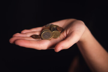 Woman holding a handful of euro coins in her palm, financial savings and money management concept for wealth and economy.