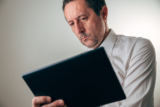 Concerned businessman analyzing financial data on a digital tablet, showing confusion and stress during business review, budgeting, or economic decision making. - Powered by Adobe