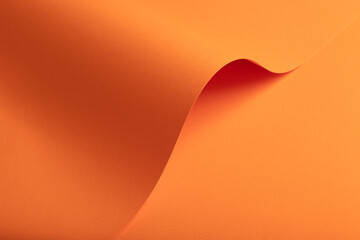 Flowing abstract paper surface in warm orange tones with a smooth curved fold forming a soft wave
