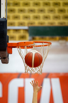 a hand throws a basketball into a basket