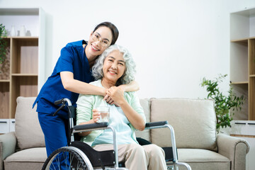 Asian nurse caring for smiling elderly woman in wheelchair at home. Senior care, home healthcare, nursing support, compassion, caregiver service concept